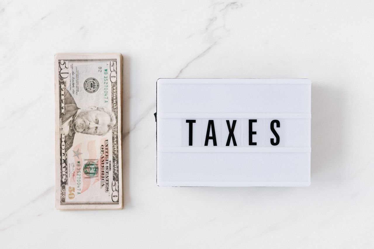 Stack of dollar bills beside a TAXES sign, representing tariff costs for Ontario businesses