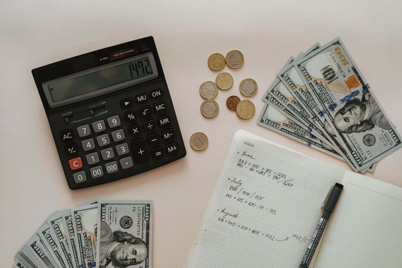 Calculator, coins and notebook used for cash flow forecasting in a startup or small business