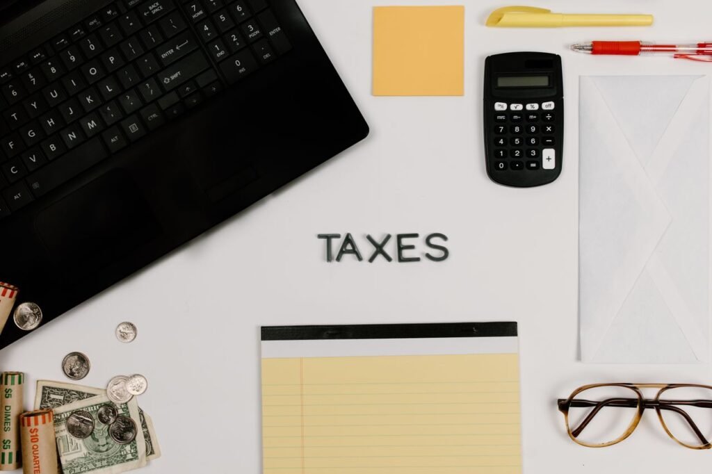 Calculator beside a laptop on a desk, tools for AI bookkeeping in a small business